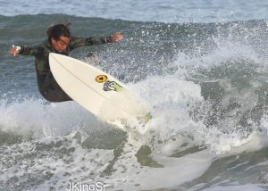 A man surfing in all-black clothing