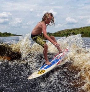 A man with long, dirty blond hair surfing